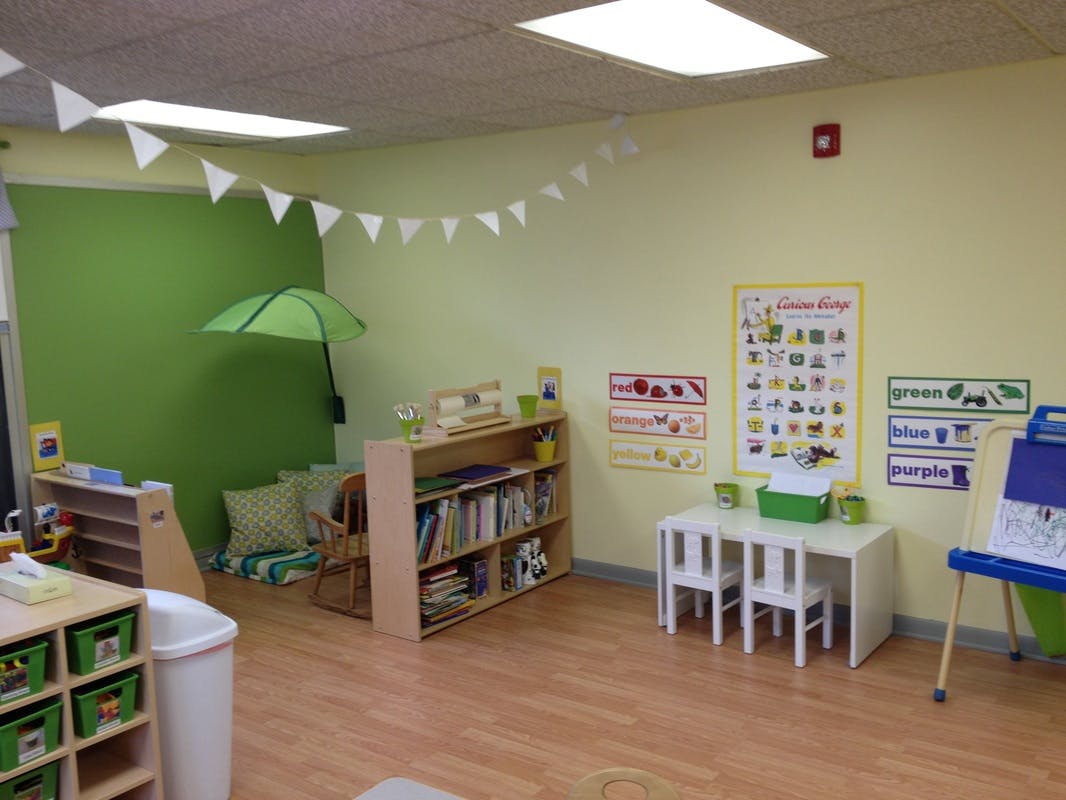 Classroom with small tables, chairs, bookshelves, and wall decorations
