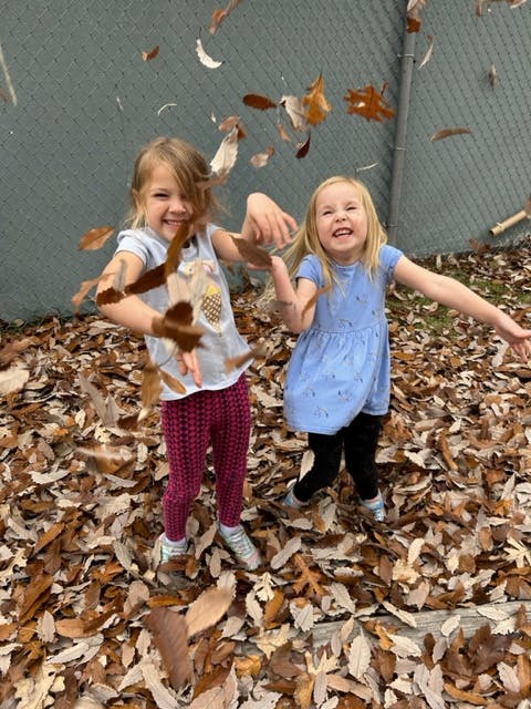 Two children playing in fallen leaves