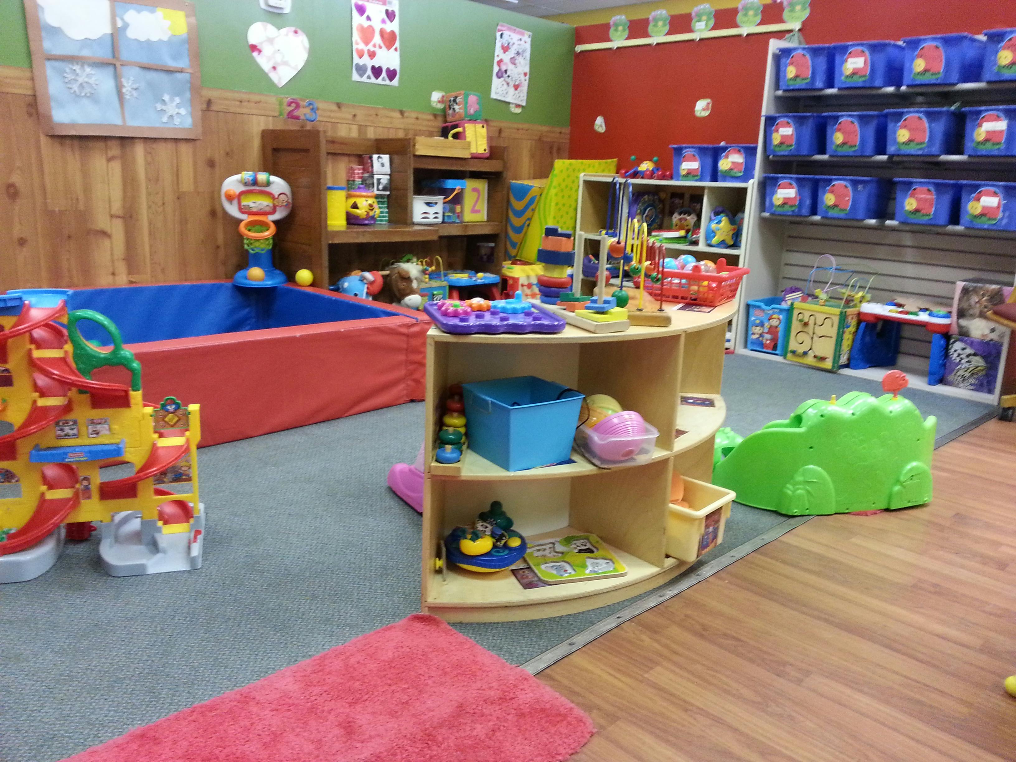 Playroom with a ball pit, shelves of toys, and a green ride-on toy