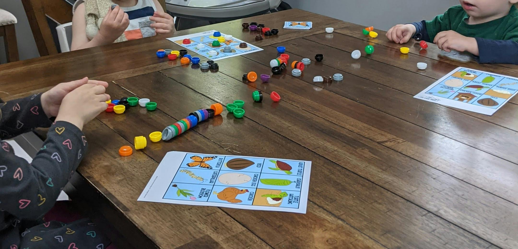 Children playing with colorful game pieces and cards on a wooden table