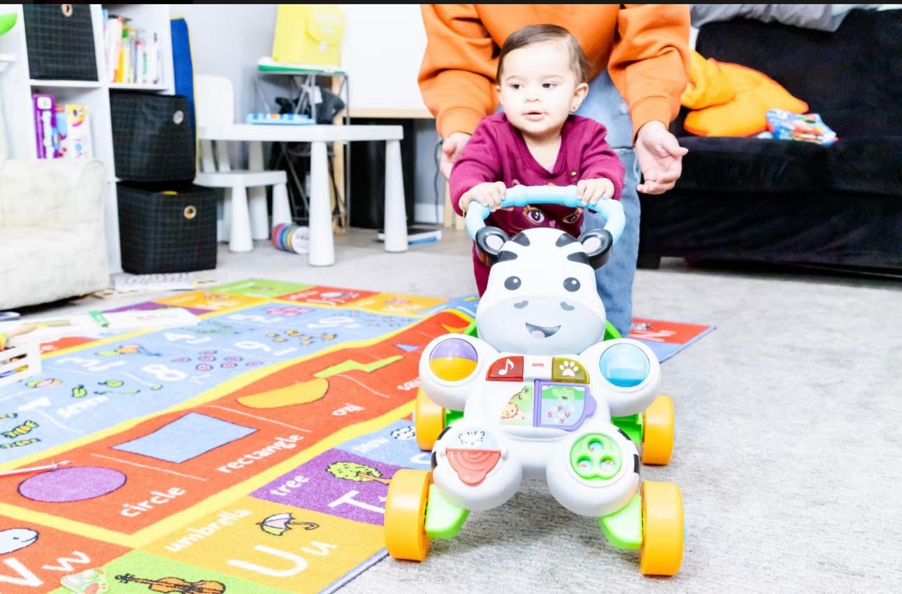 Person helping a child use a baby walker
