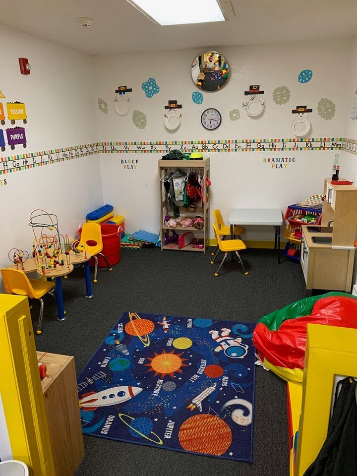 Children's play area with tables, chairs, toys, and a space-themed rug