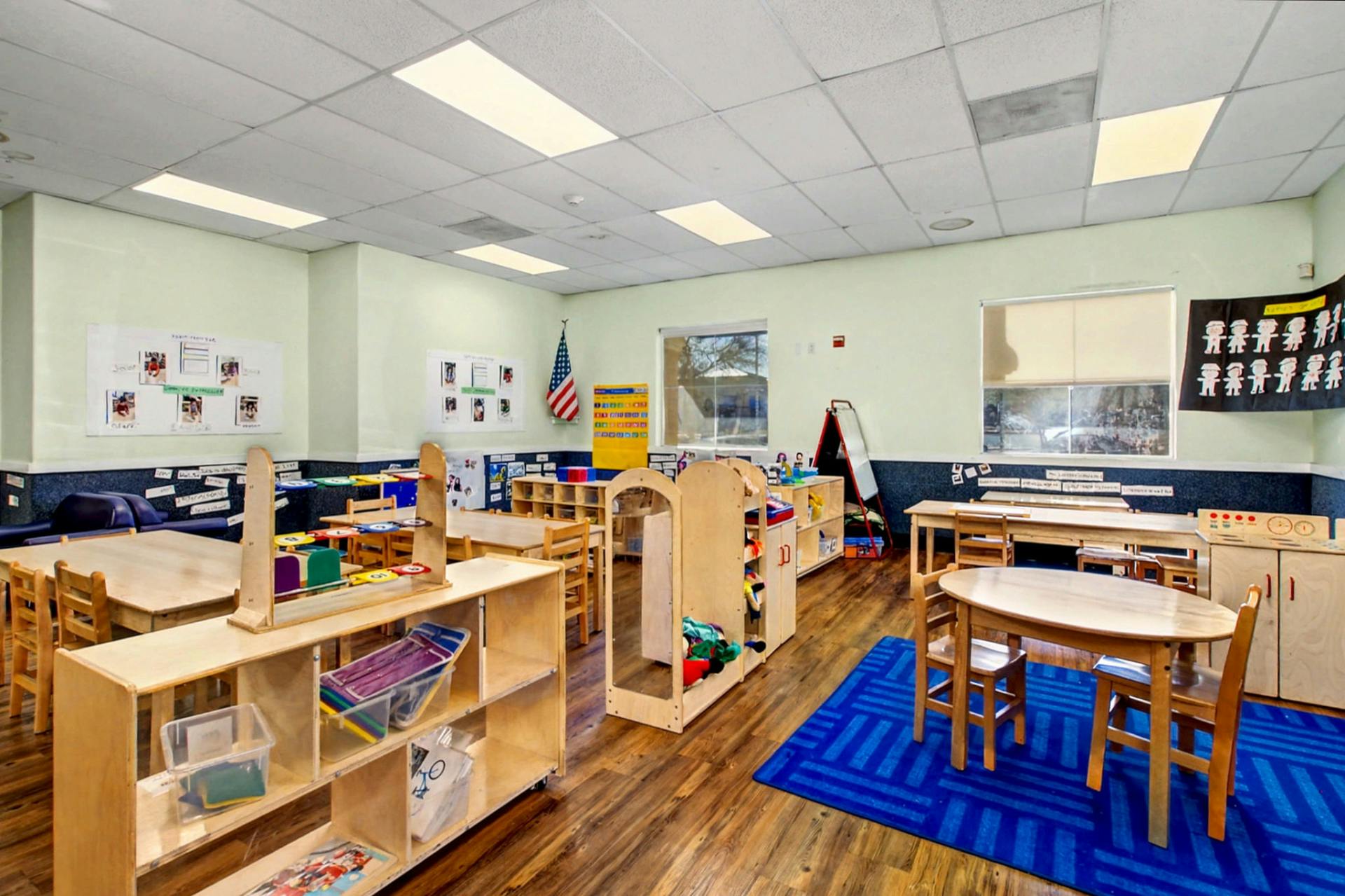 Empty classroom with small tables, chairs, and shelves