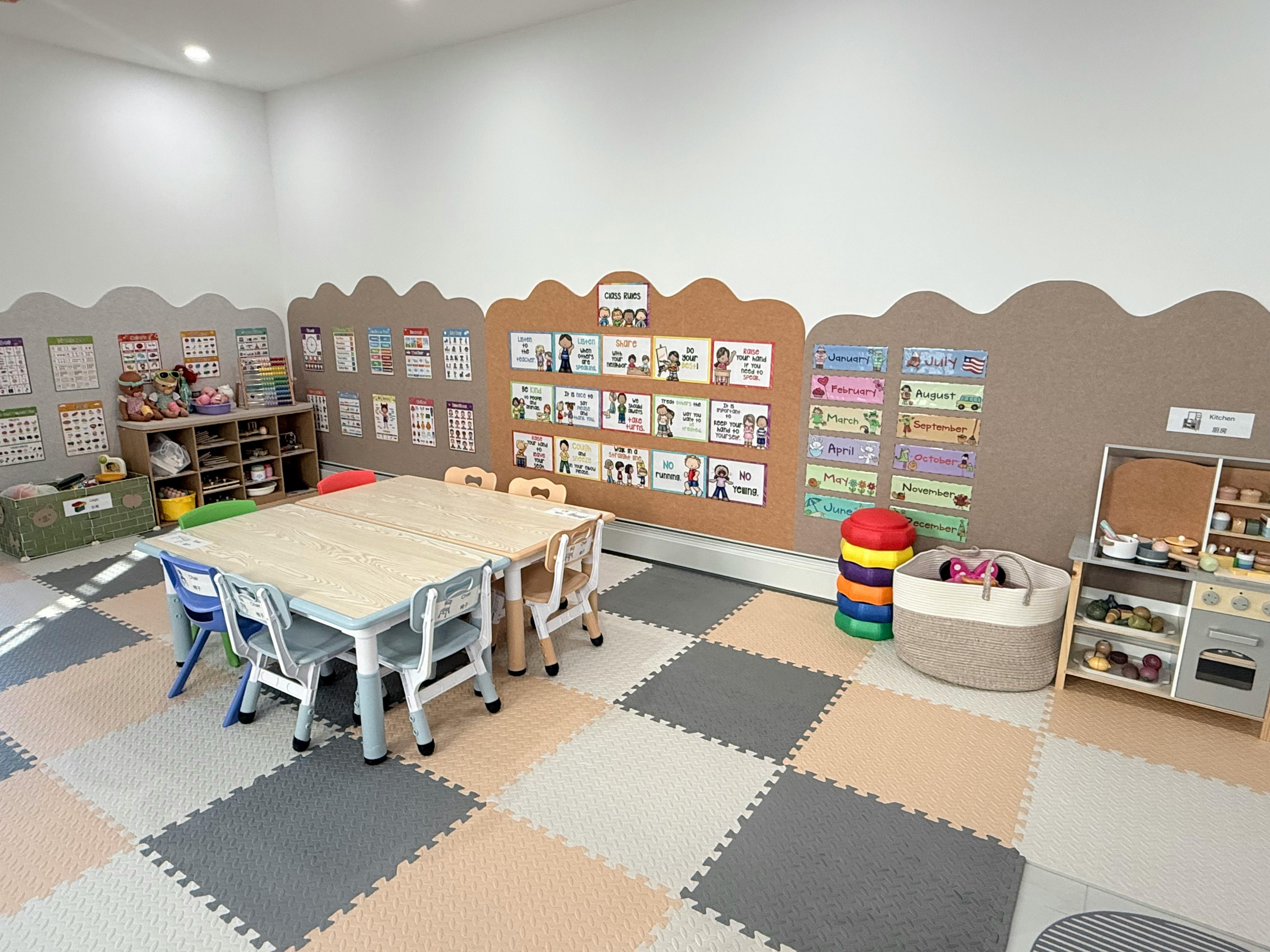 Classroom with small tables and chairs, play kitchen, and wall displays