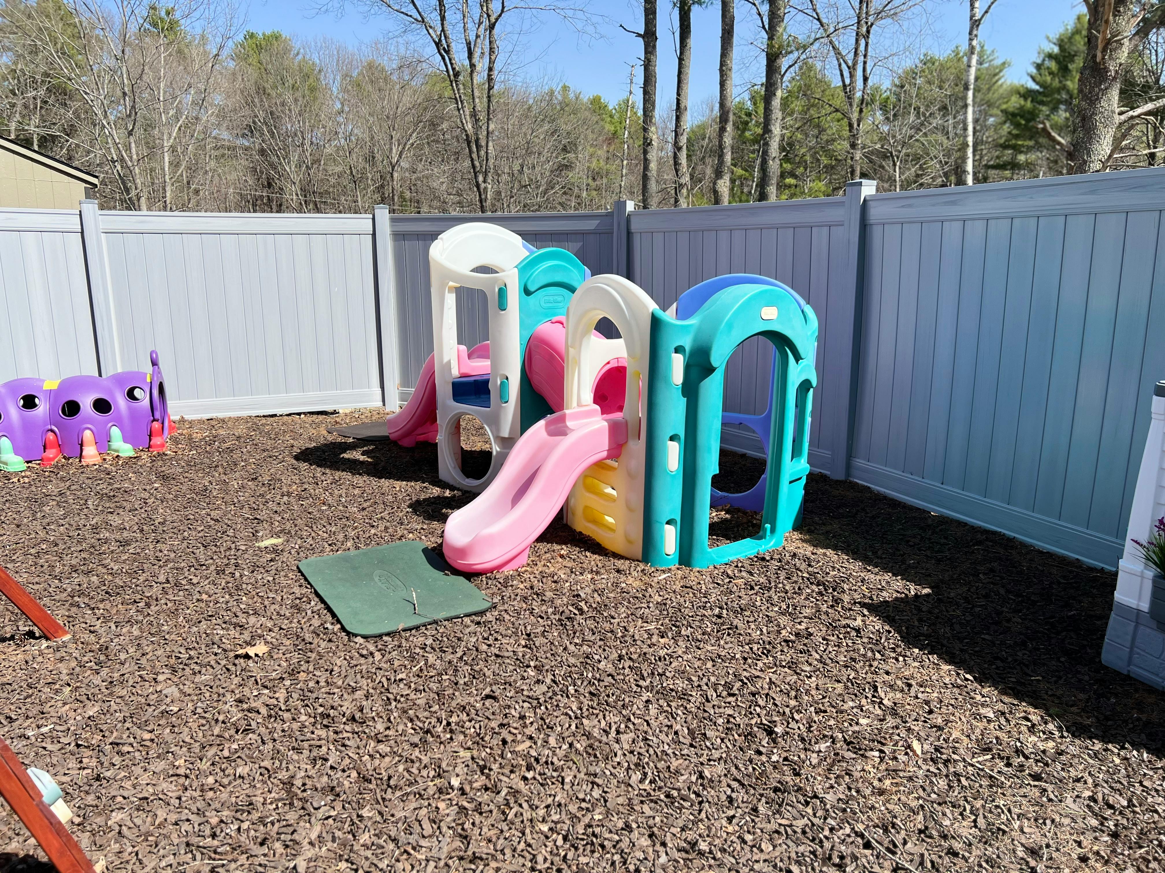 Small plastic playground slide and climbing structure on wood chips