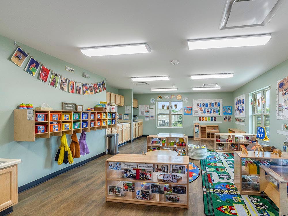 An empty toddler classroom with learning materials and cubbies