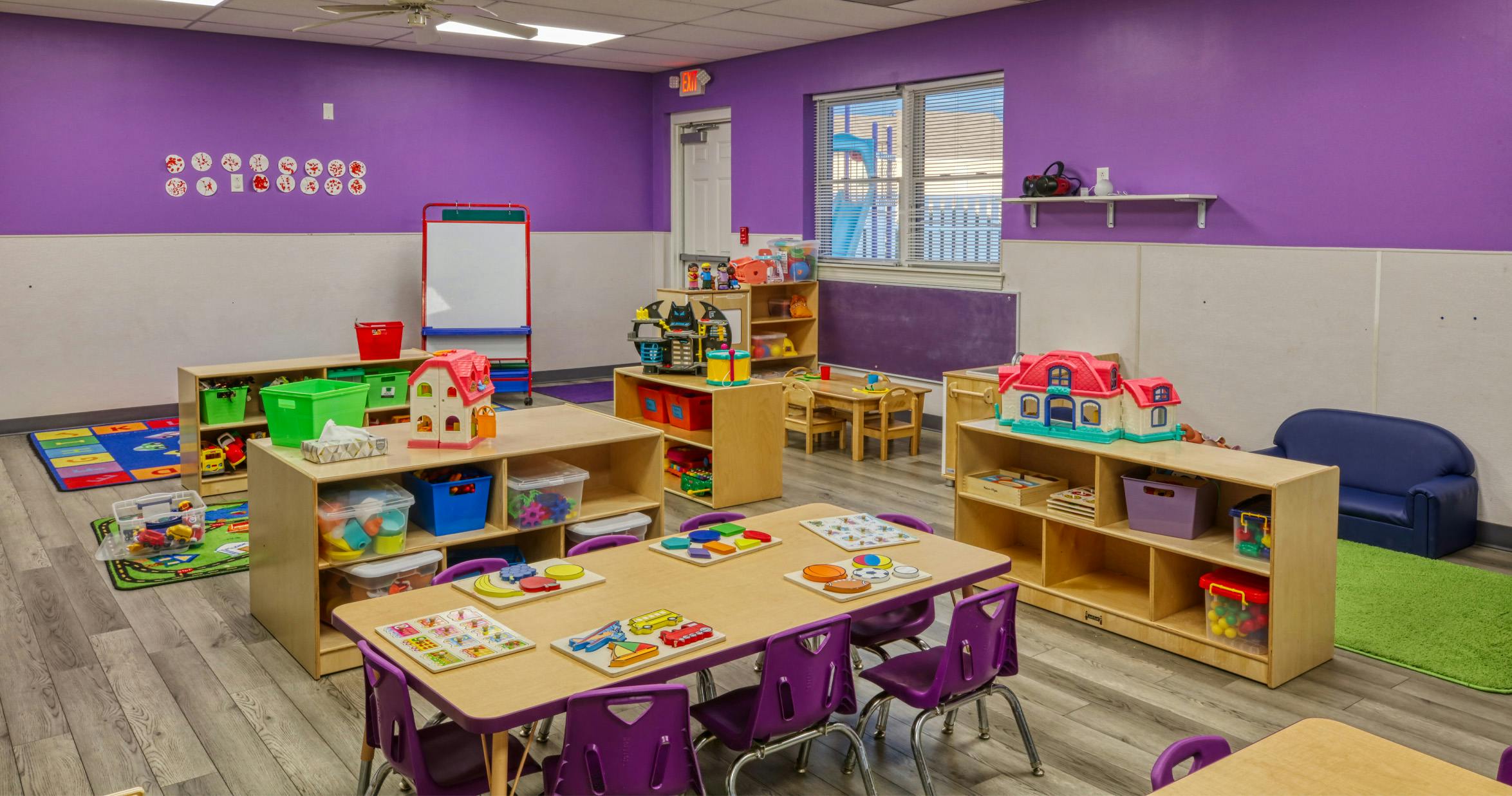 Classroom with purple and white walls, tables, and toys