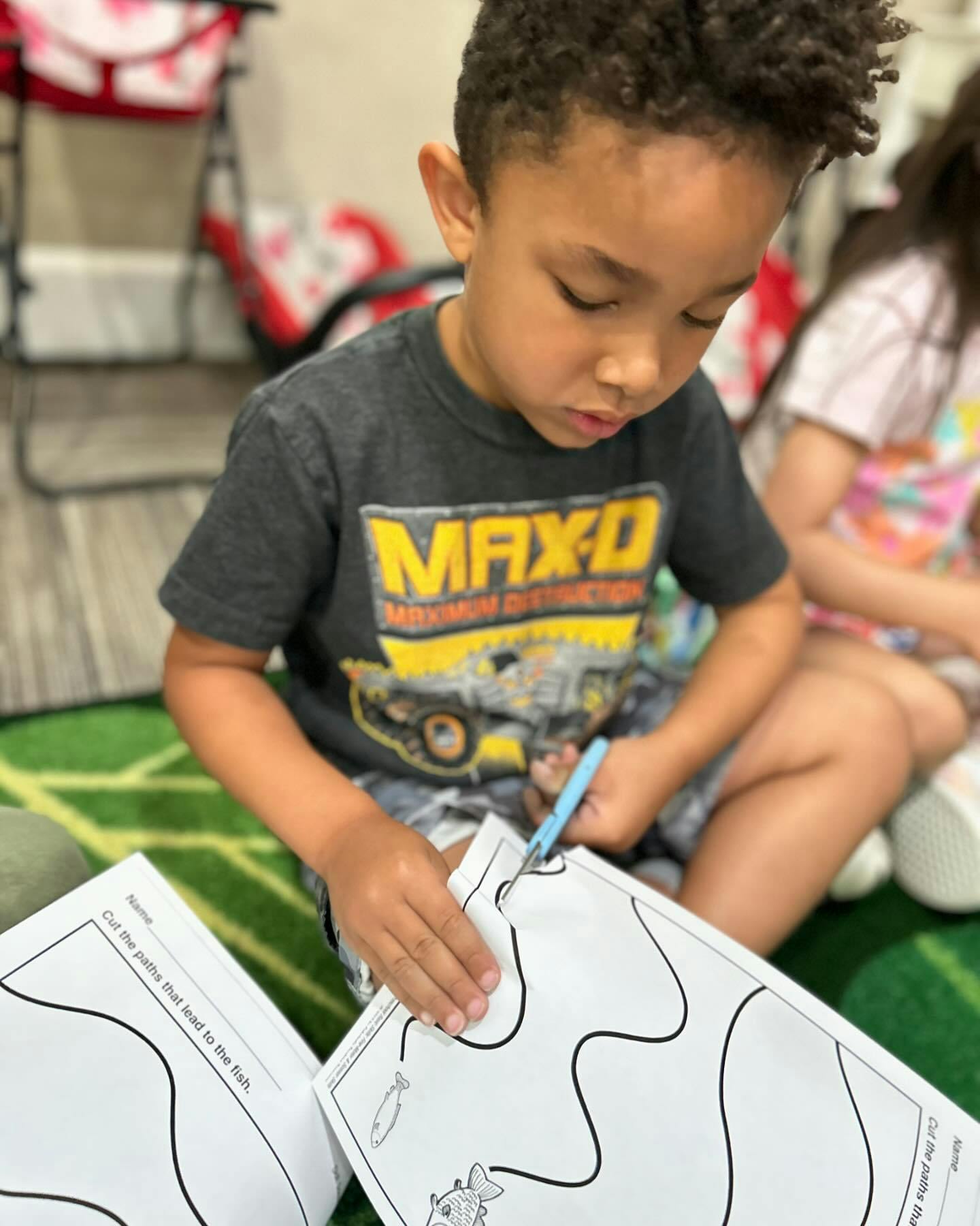 A child cutting a paper worksheet with scissors