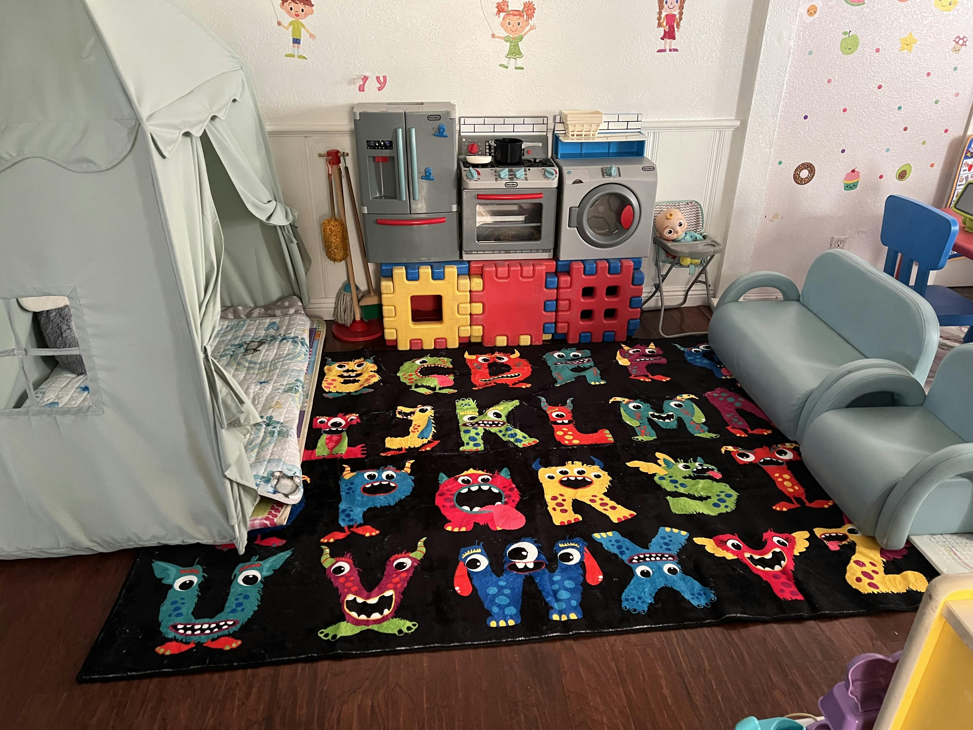 Playroom with alphabet monster rug, toy kitchen, and play tent