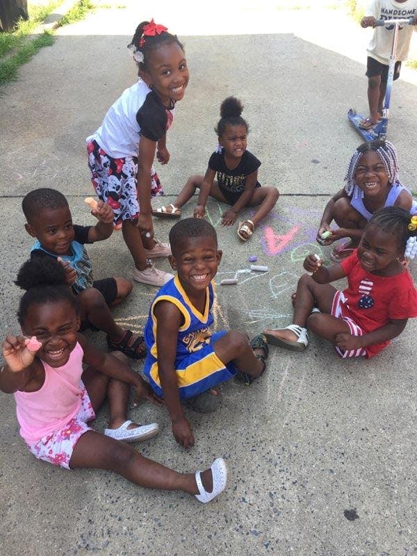 Group of children sitting and standing on pavement with chalk drawings