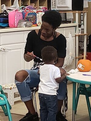Person painting with a child in a classroom