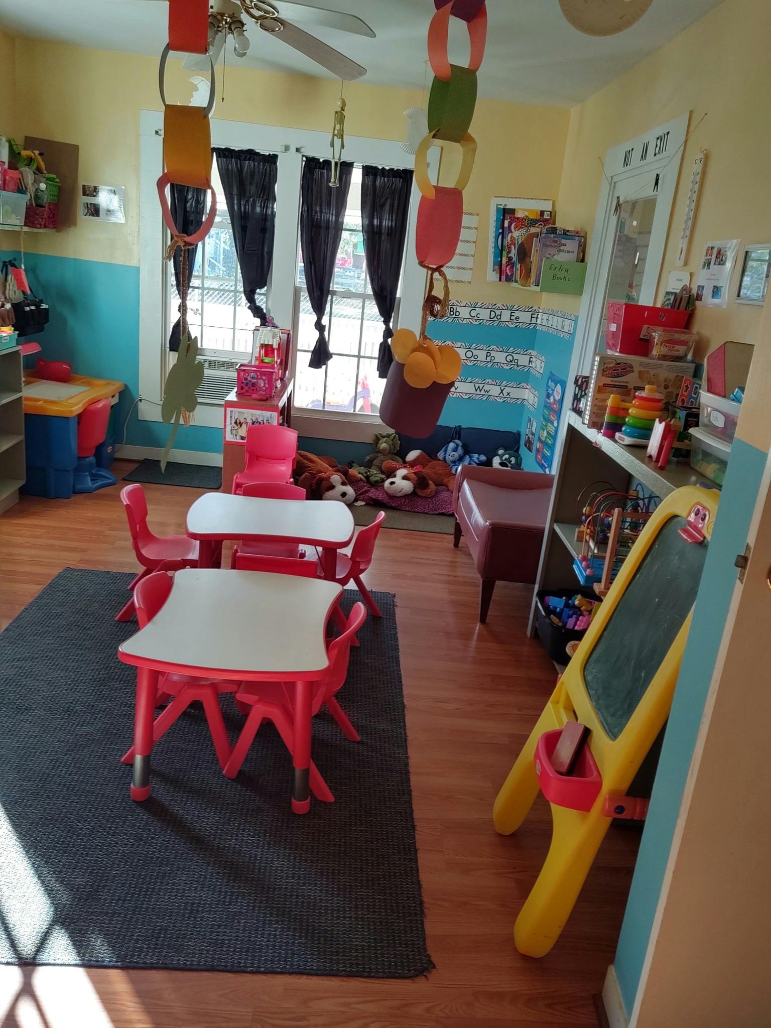 Classroom with small red tables and chairs, toys, and a window