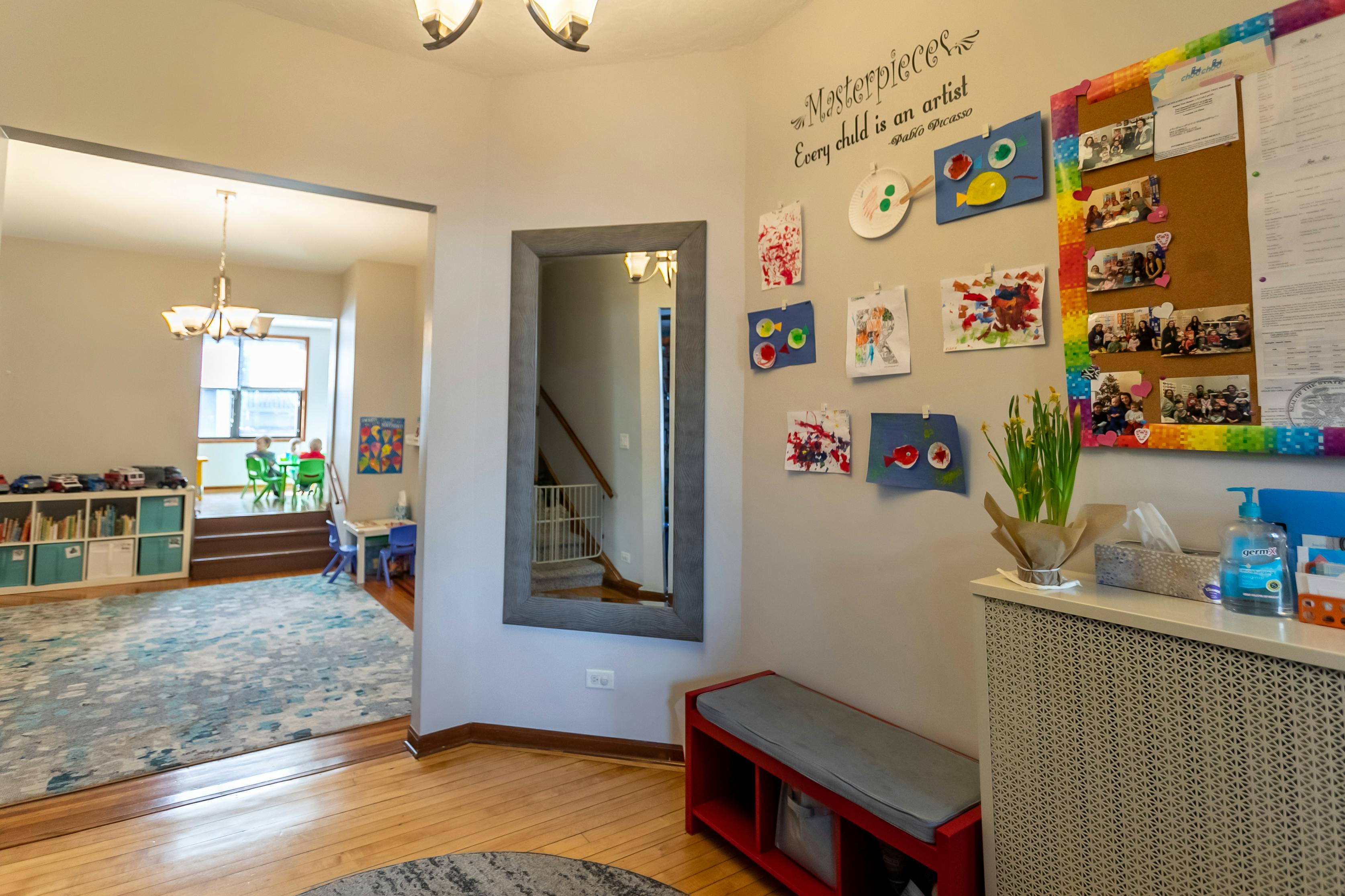 Hallway with mirror, children's artwork on wall, and view into another room