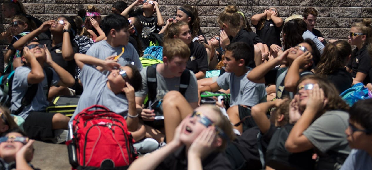 Group of people looking up with hands covering their eyes