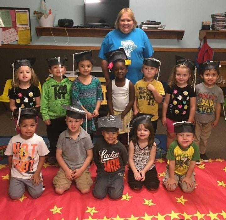 Adult and multiple children wearing graduation caps