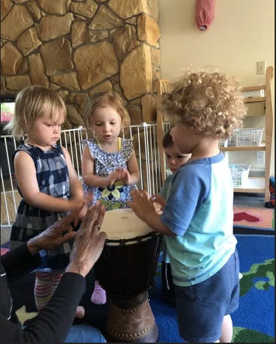 Adult and children playing a drum