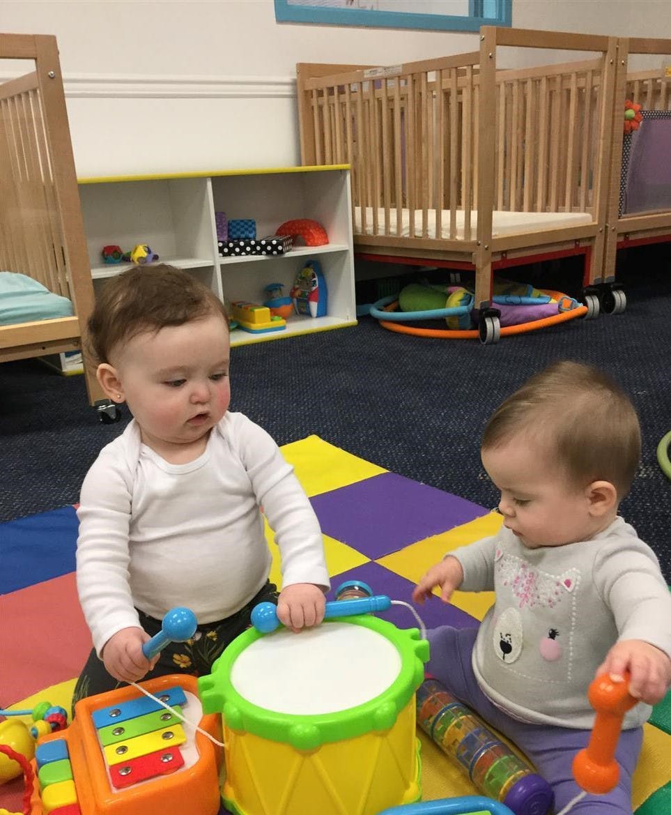Two children playing with musical toys on a colorful mat
