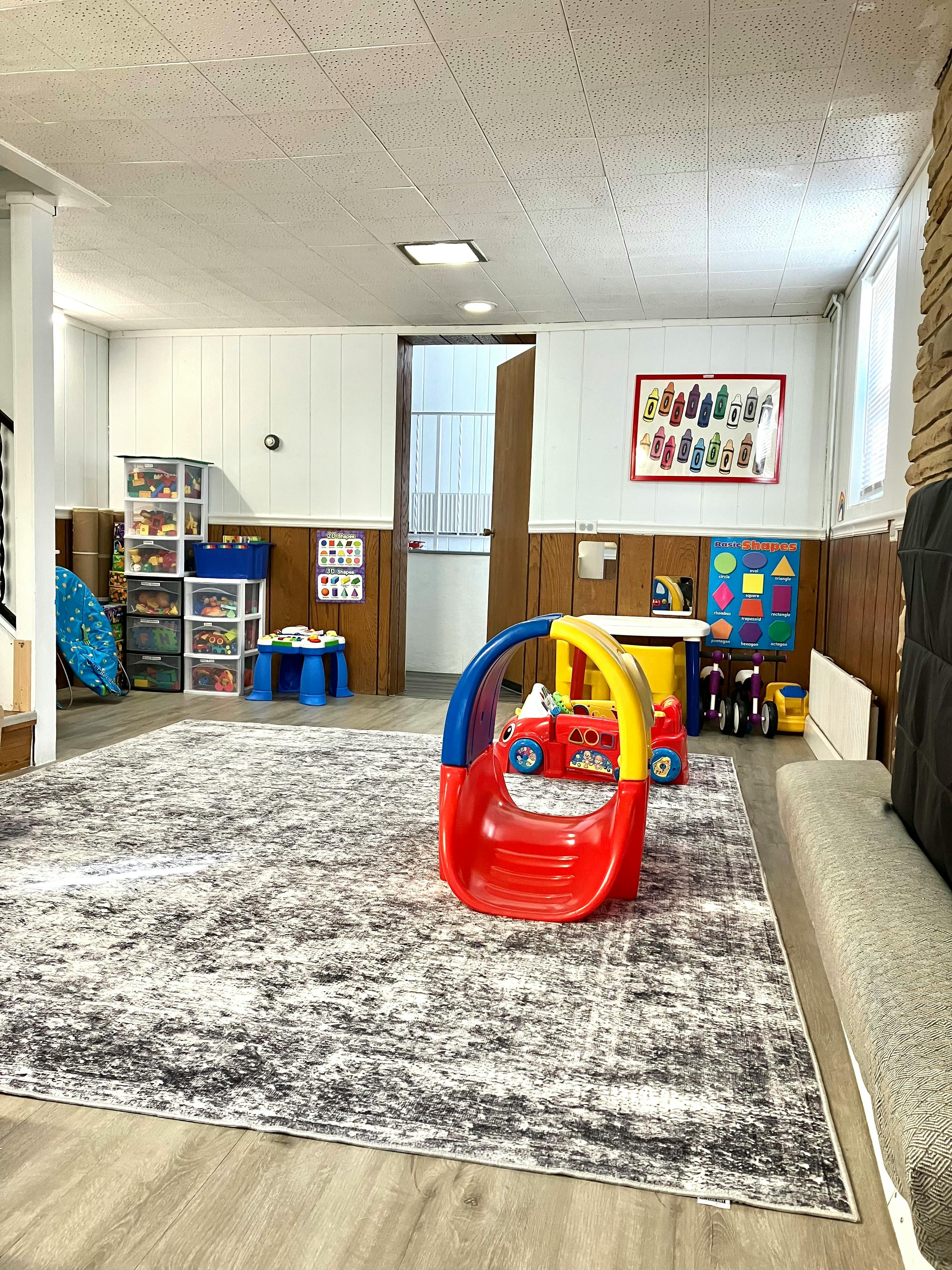 Colorful playroom with a red and yellow plastic slide, toys, and educational posters