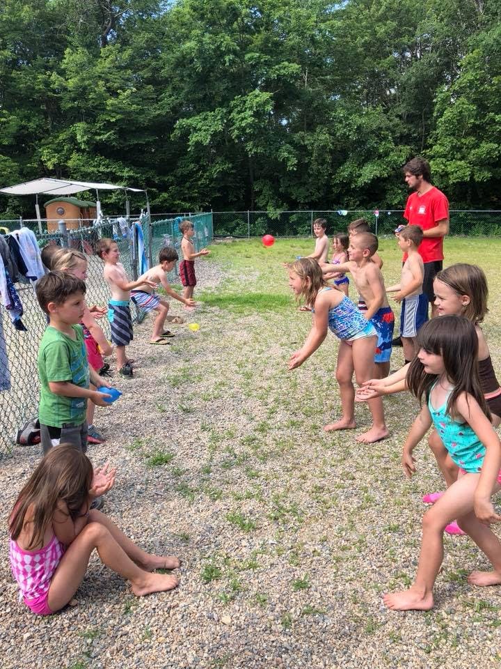 Children playing a game with a red ball and water cups outdoors