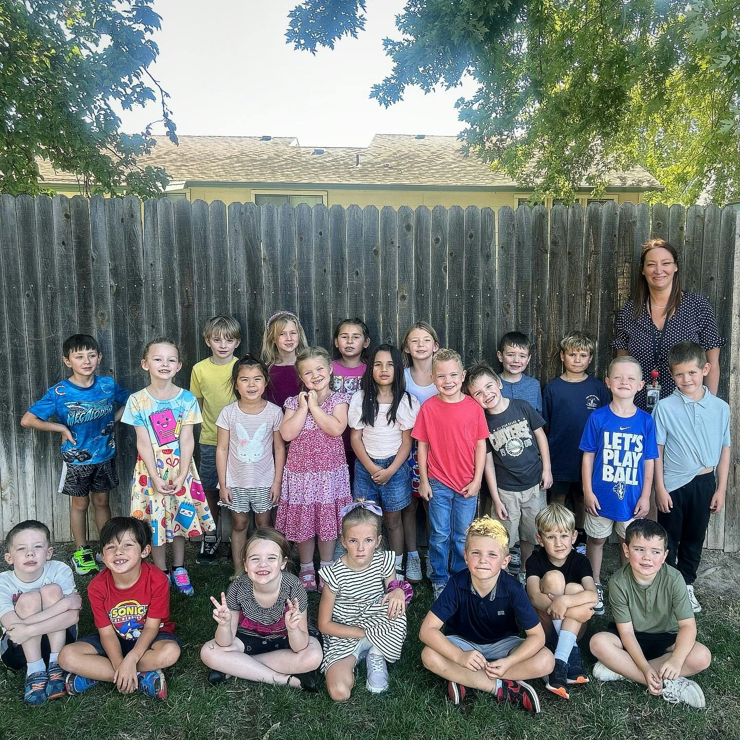 Adult and group of children posing for a photo outdoors