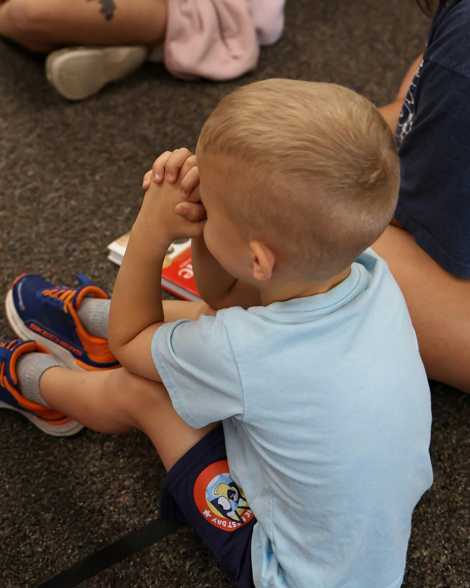 Child sitting on the ground with hands held together