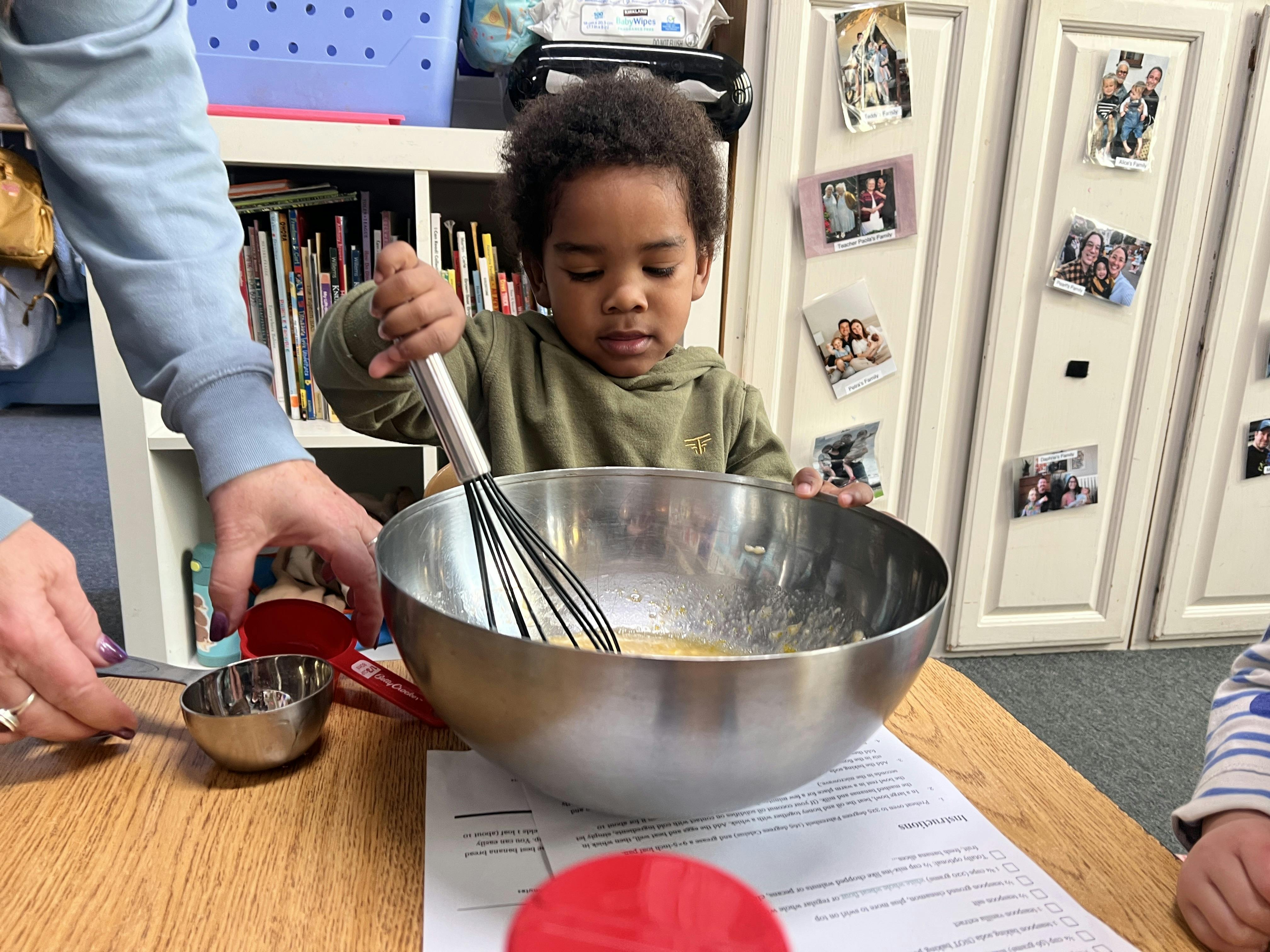 Child whisking ingredients in a metal bowl