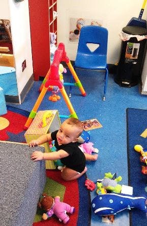Child crawling on a colorful rug in a room with toys