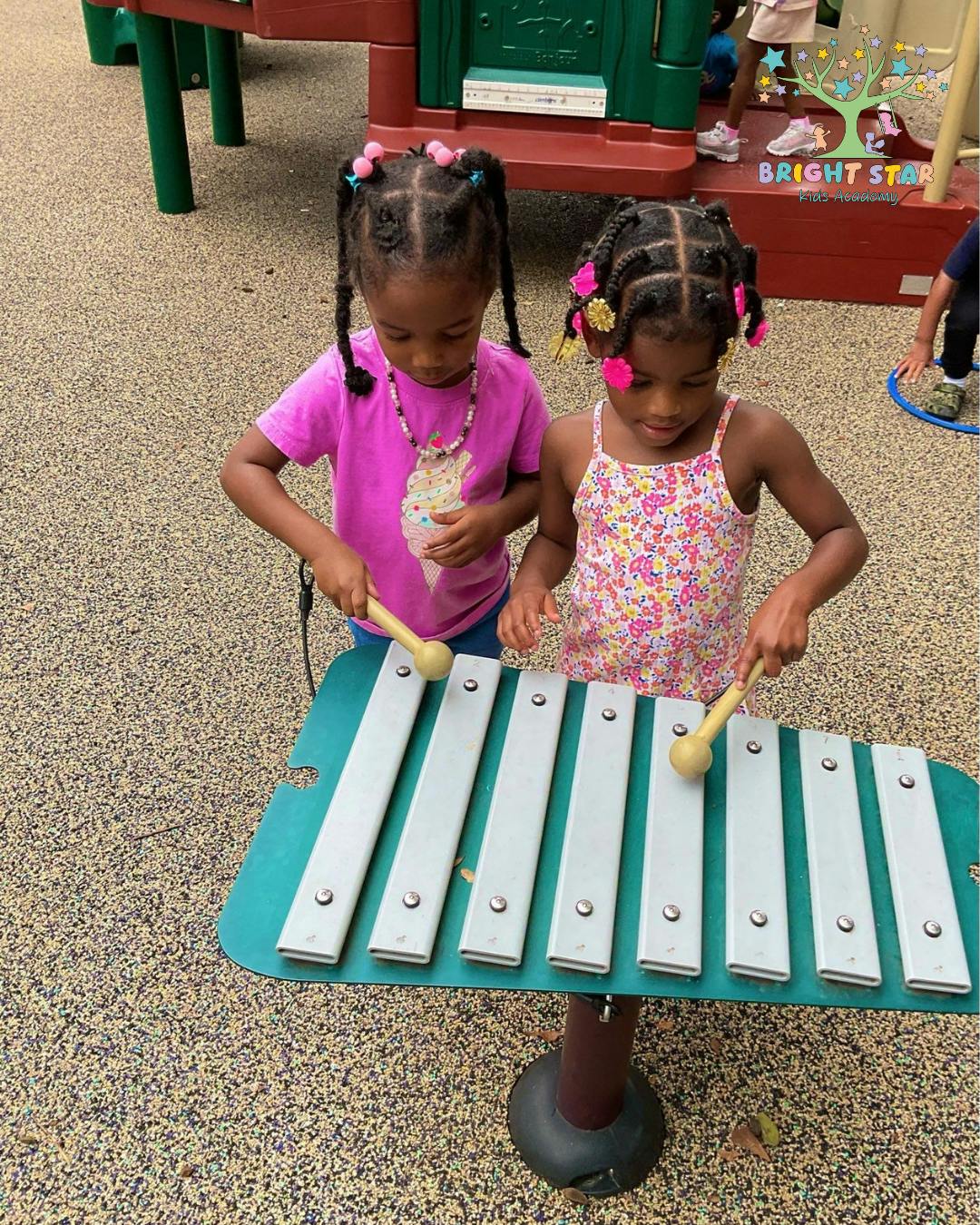 Two children playing a large outdoor xylophone