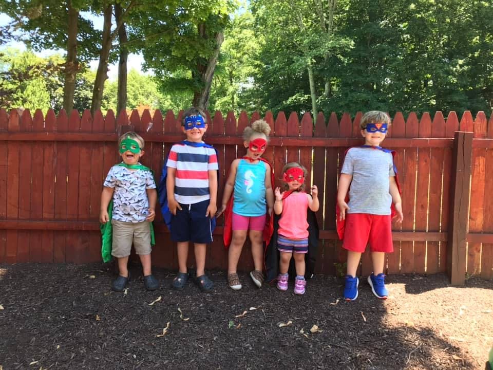 Five children in superhero masks and capes standing in a line