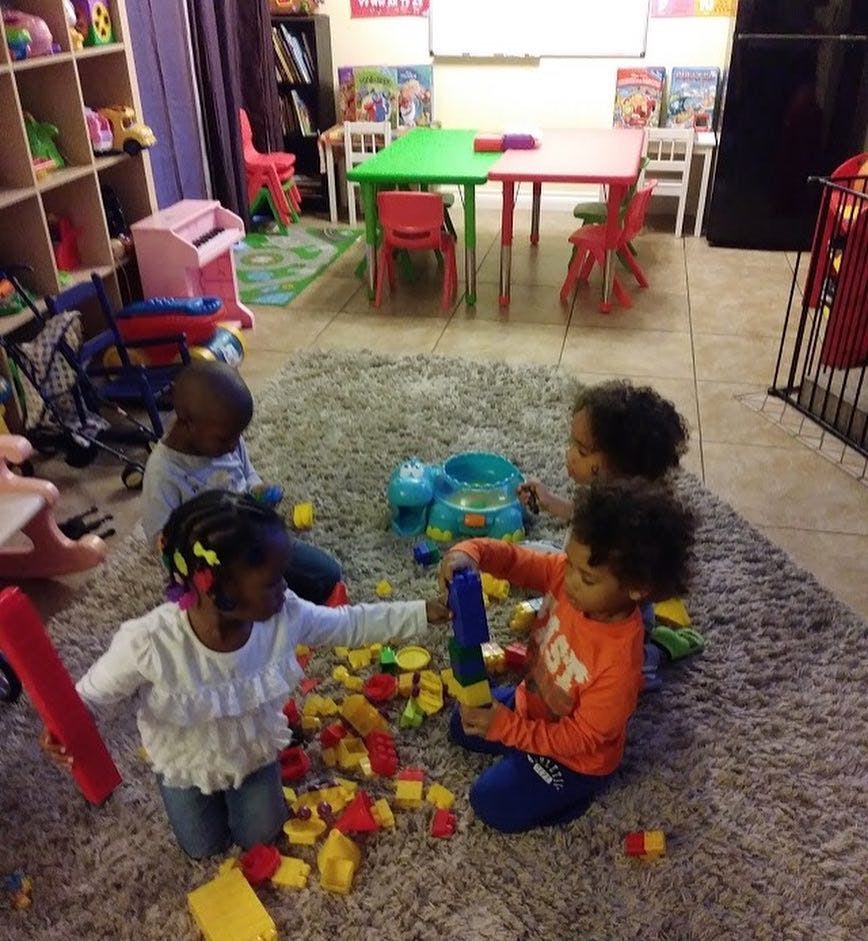 Children playing with blocks on a rug in a room with small tables and chairs