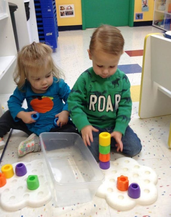 Two children playing with colorful stacking toys on the floor