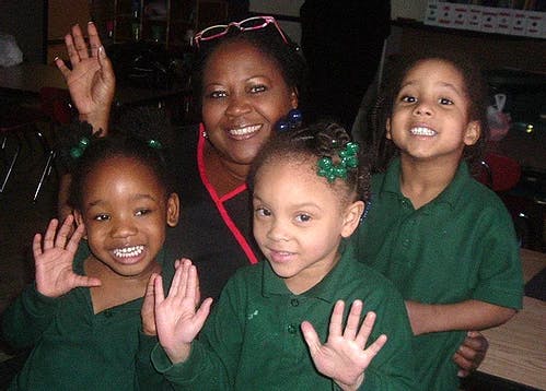 Adult and three children waving