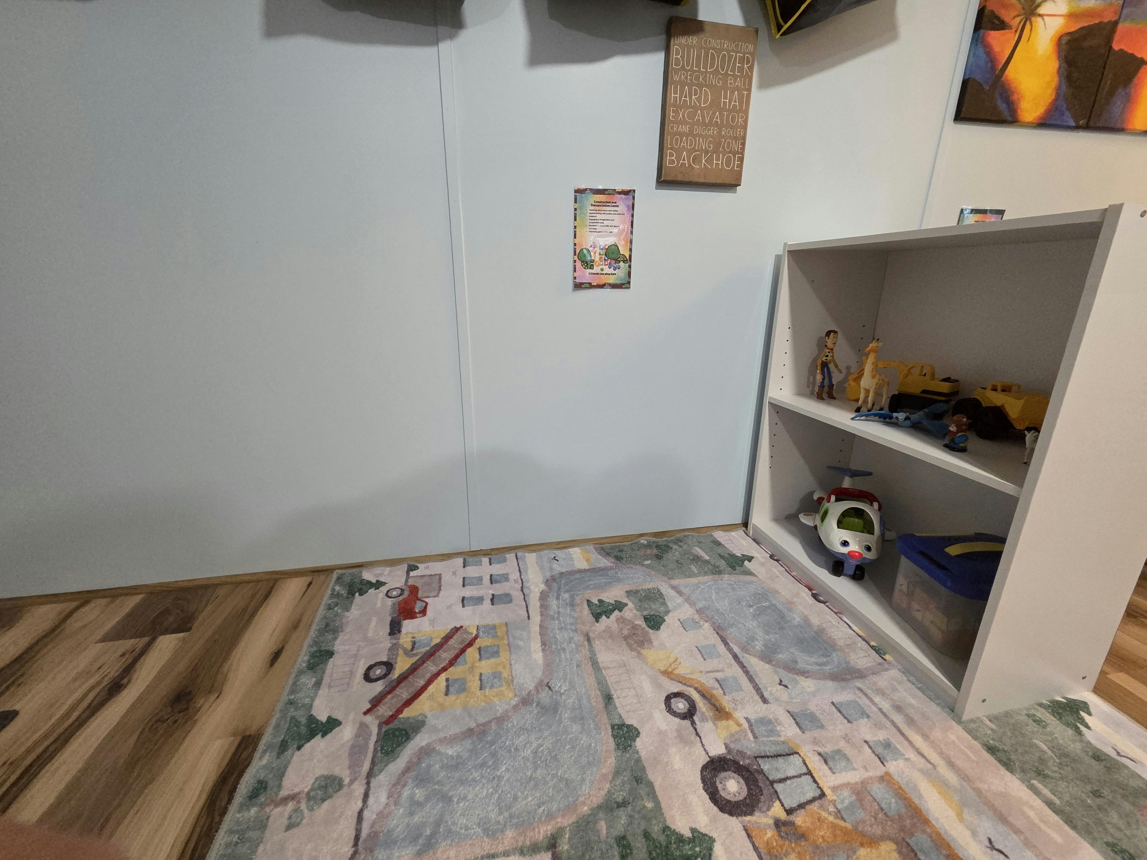 Playroom with a toy shelf and a street-themed rug on the floor