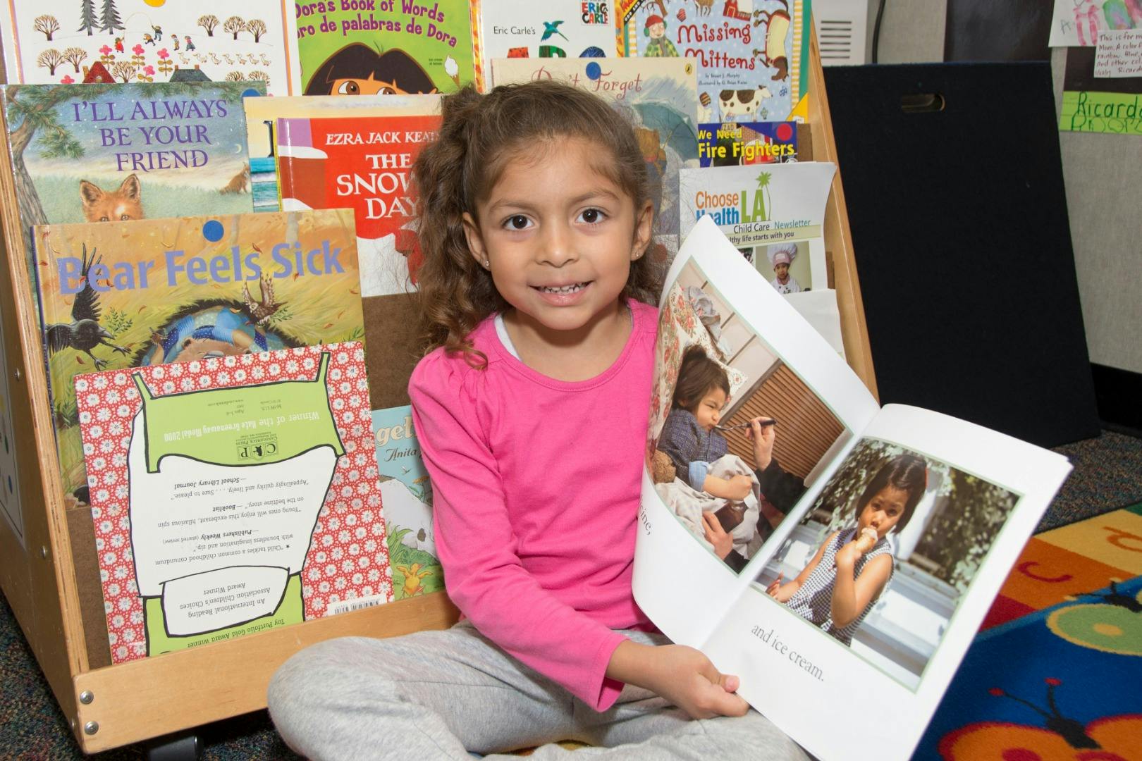 Child sitting on floor holding an open book with photos