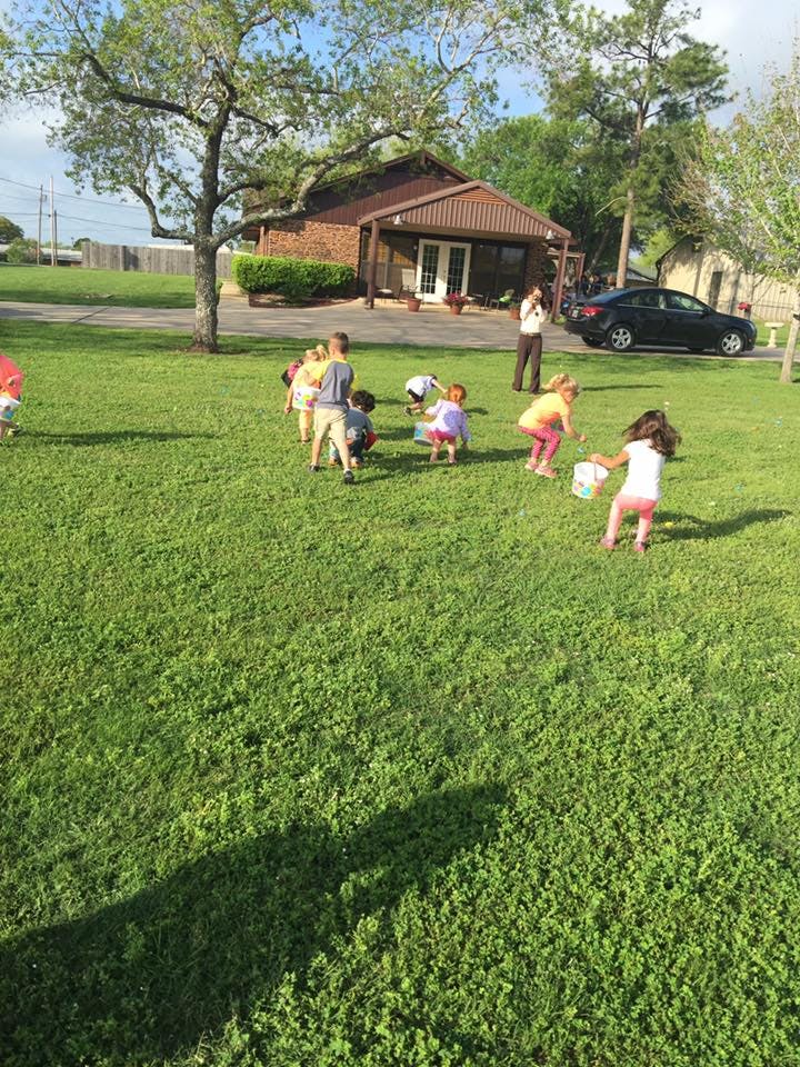 Children on a grassy lawn with a person standing in the background