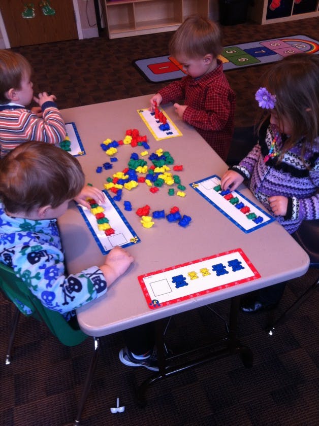 Four children playing with colorful blocks at a table
