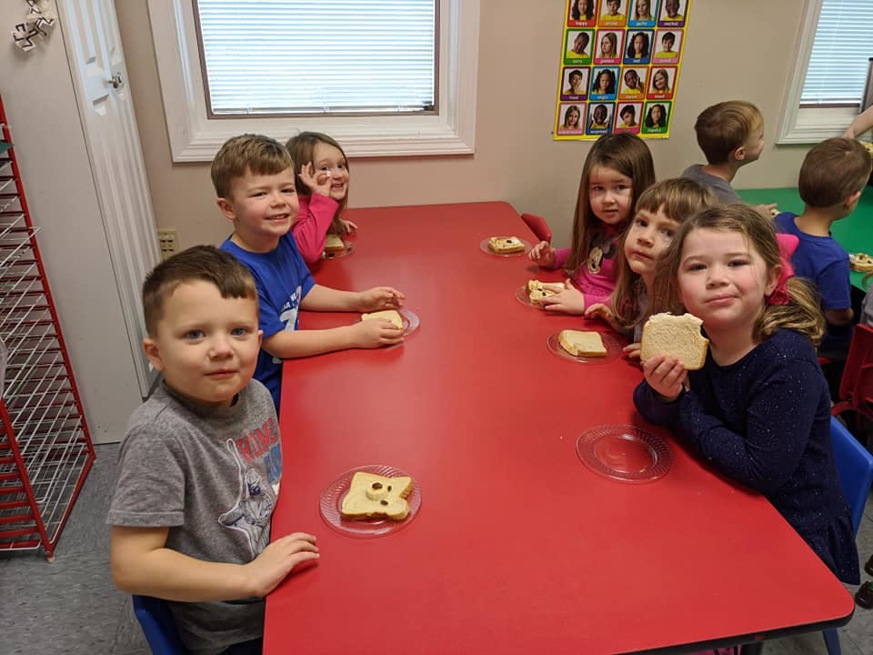 Children sitting at a red table with snacks
