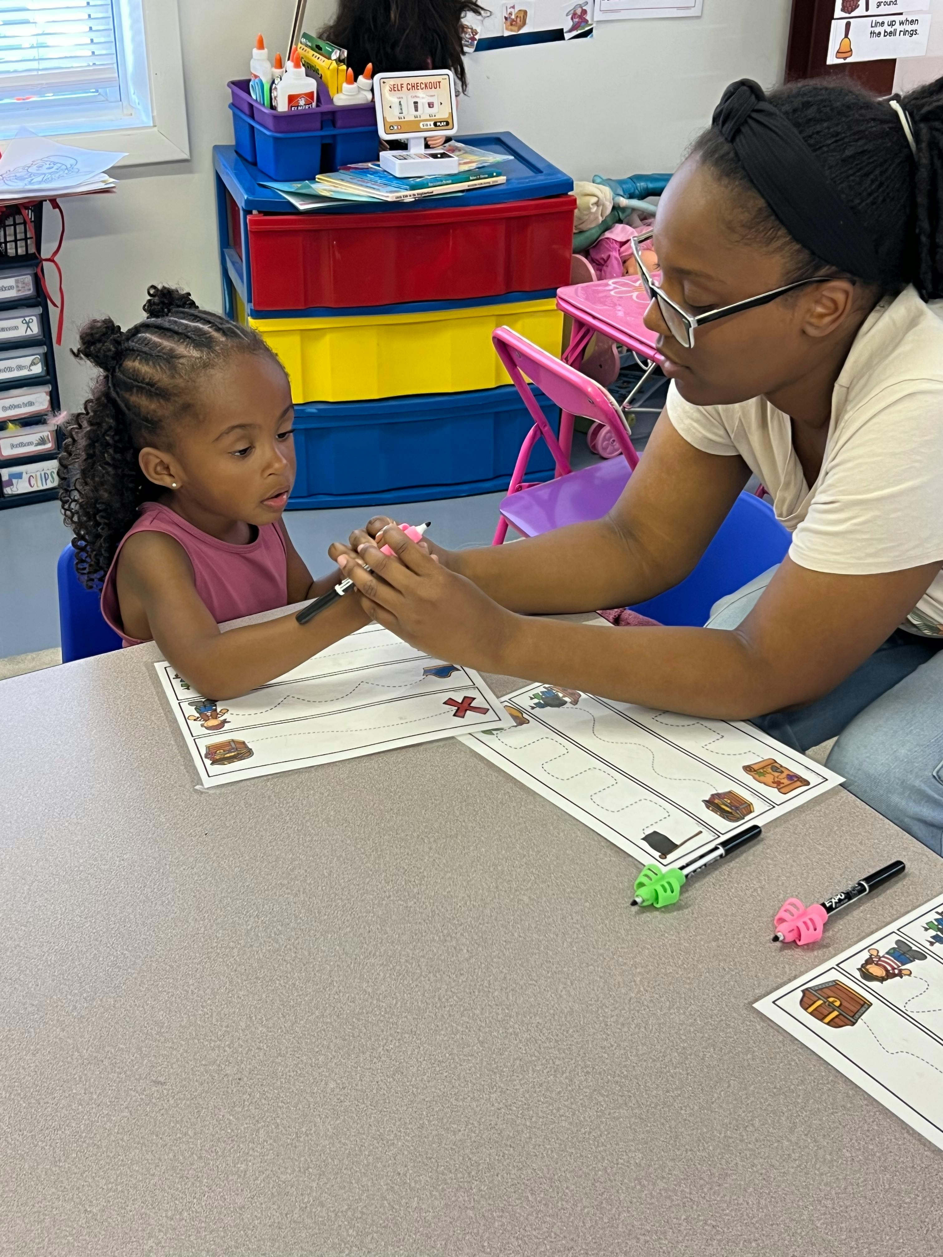 A person helping a child with writing on a worksheet