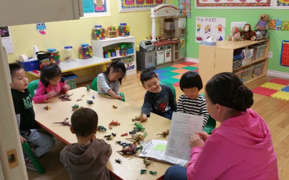 Adult and children at a table with toys in a classroom