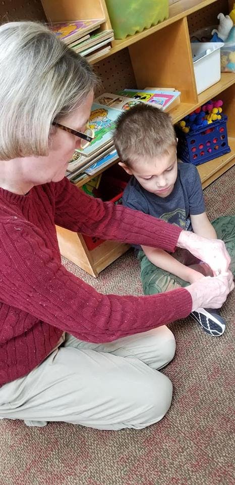 Adult and child sitting on floor, adult holding child's hands