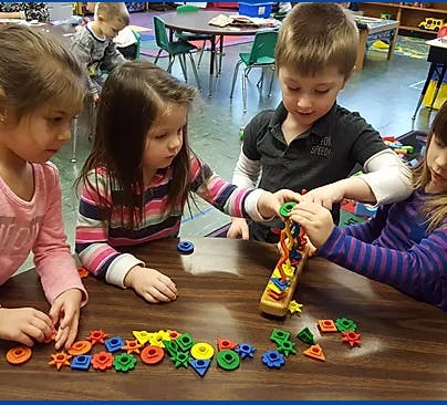 Children playing with colorful interlocking toys at a table