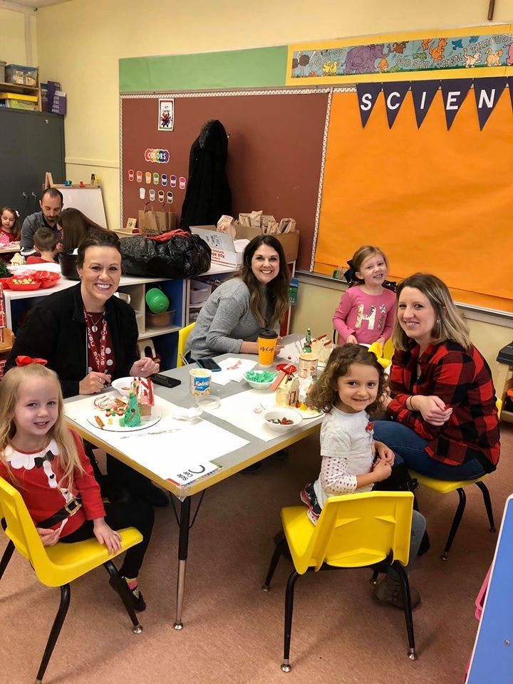 Adults and children sitting at tables in a classroom
