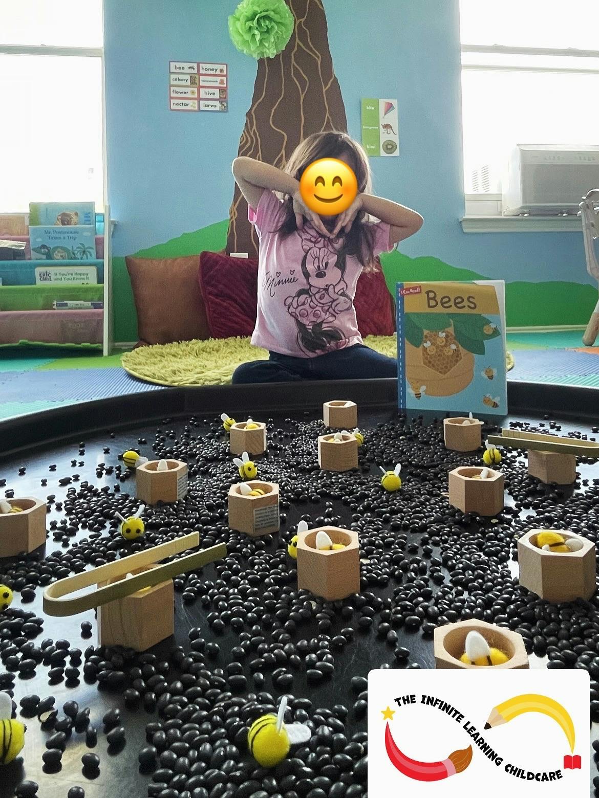 Child sitting on floor with hands near head, book titled "Bees" nearby