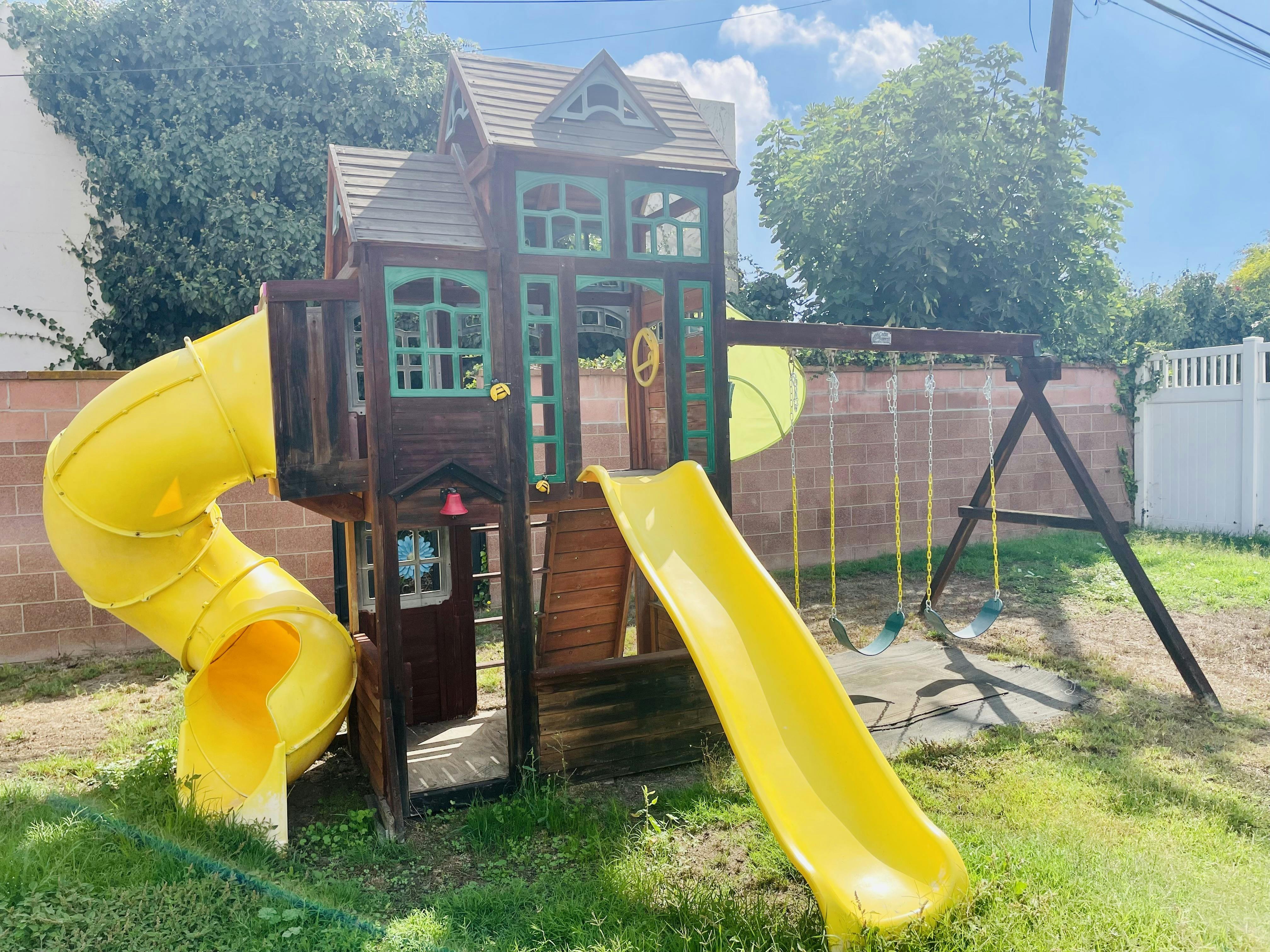 Wooden playground with yellow slides and swings
