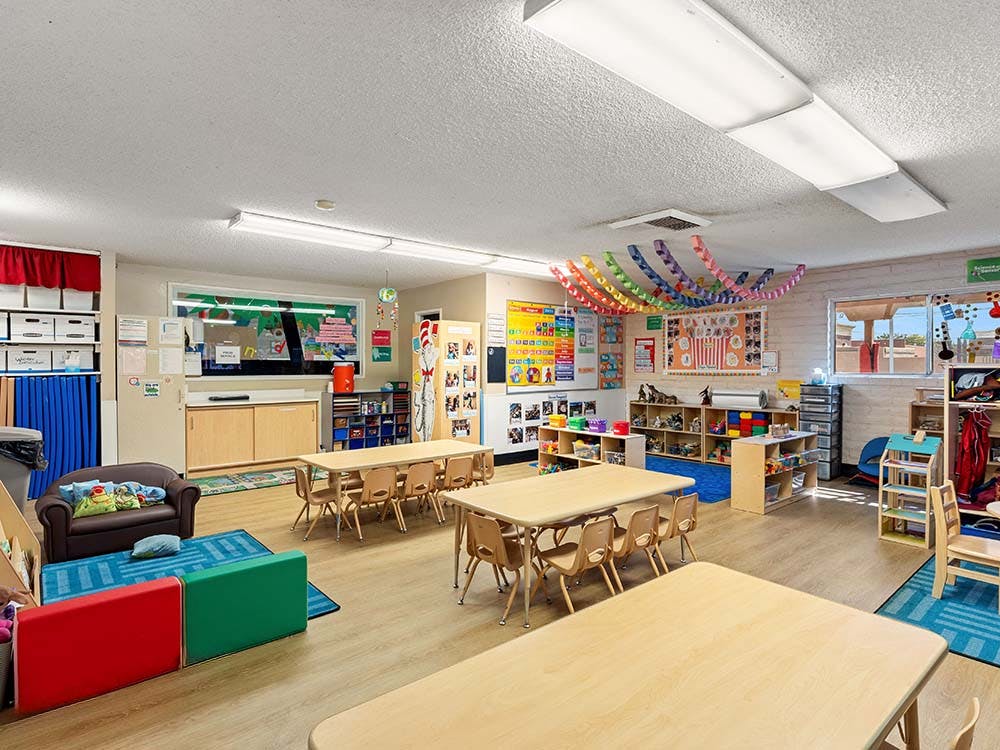 Classroom with child-sized tables and chairs, colorful decorations, and play areas
