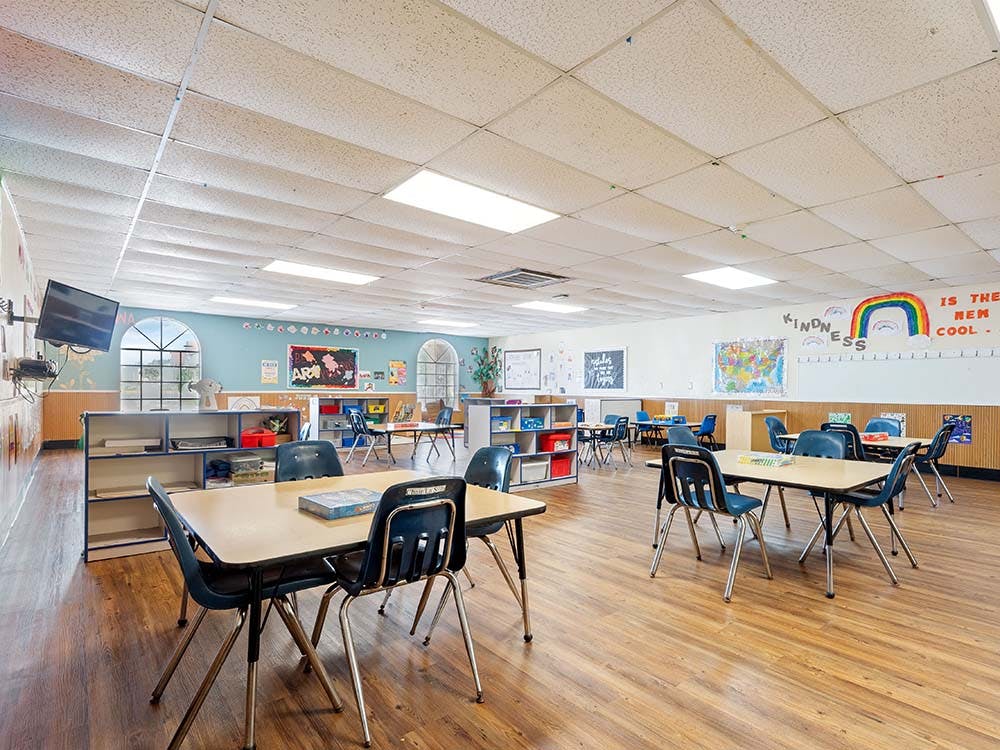 Empty classroom with small tables and chairs, and decorations on walls