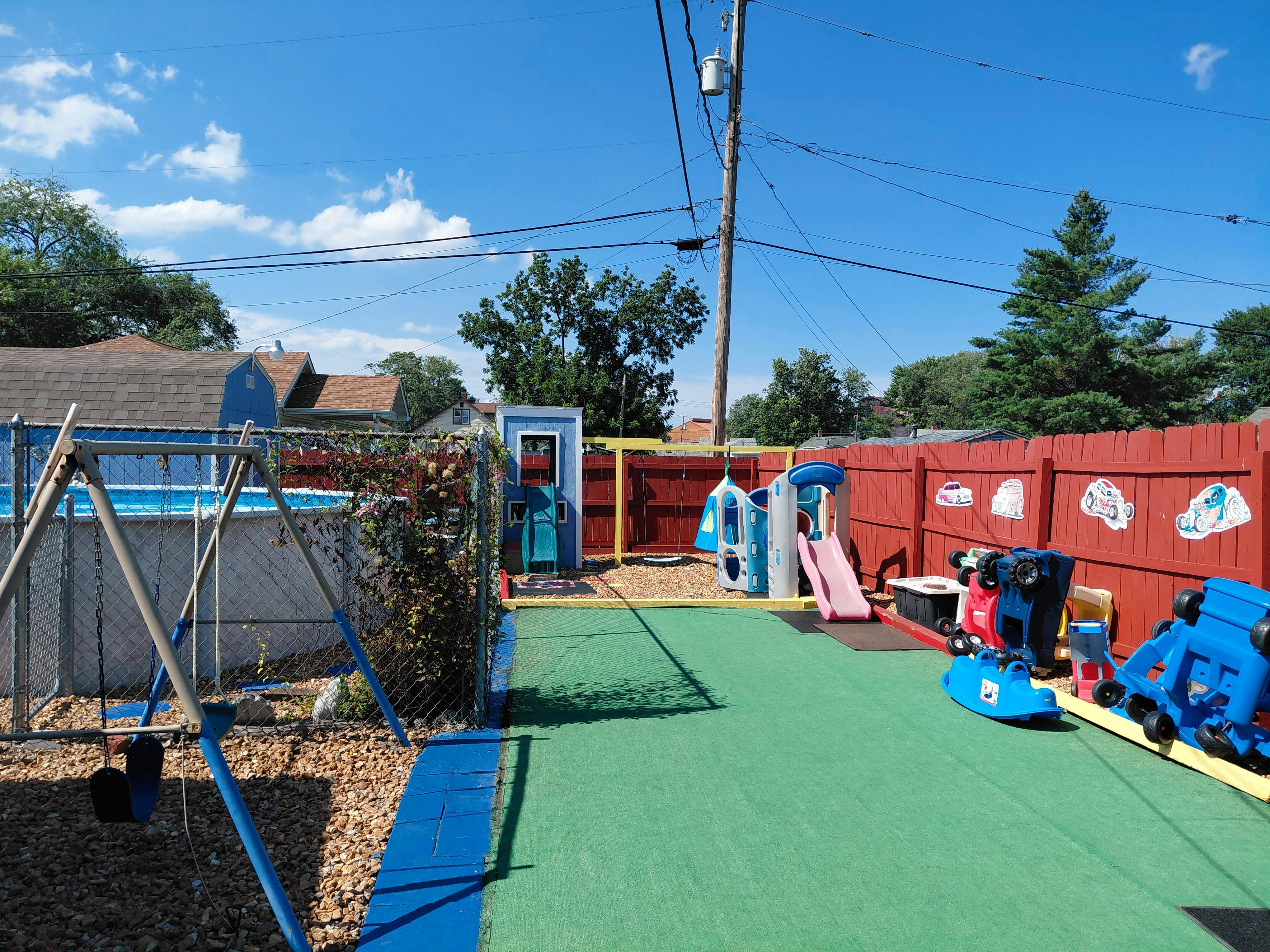 Outdoor play area with a swing set, pool, and various toys