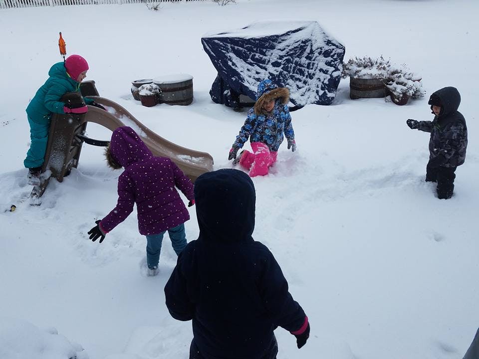 Children playing in the snow with a slide