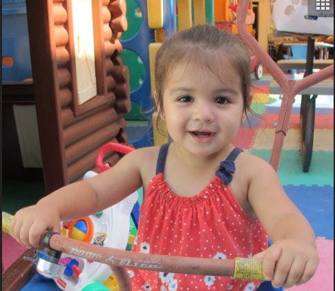 Child in a red polka dot top holding handlebars