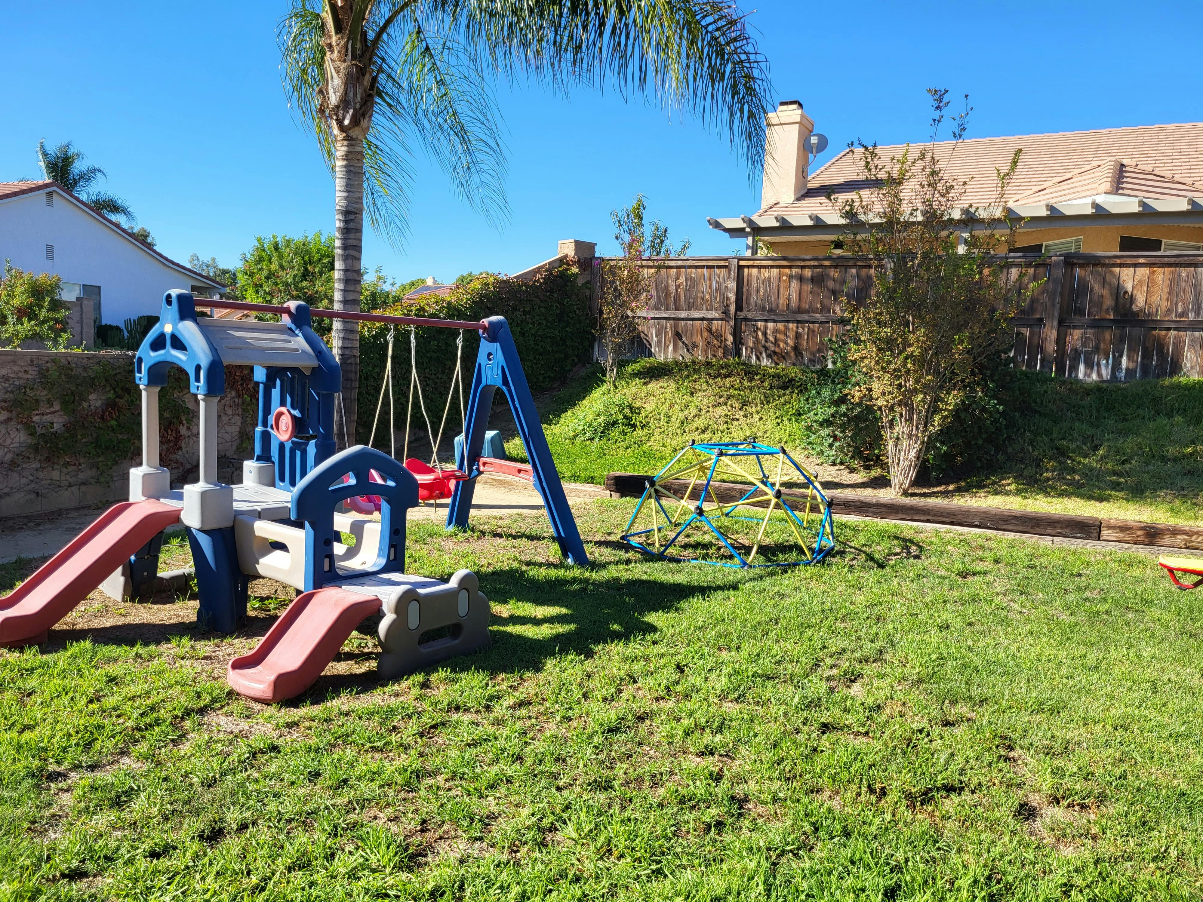 Playground with slides, swings, and climbing dome on grass
